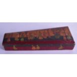 AN INDIAN PAPIER MACHE PEN BOX AND COVER depicting figures in various pursuits. 34 cm x 12.5 cm.