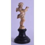 A 19TH CENTURY EUROPEAN CARVED DIEPPE IVORY FIGURE OF A PUTTI modelled holding an open book, upon an