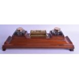 A LATE VICTORIAN CARVED MAHOGANY DESK STAND with dual inkwell and rotating brass calendar. 46 cm