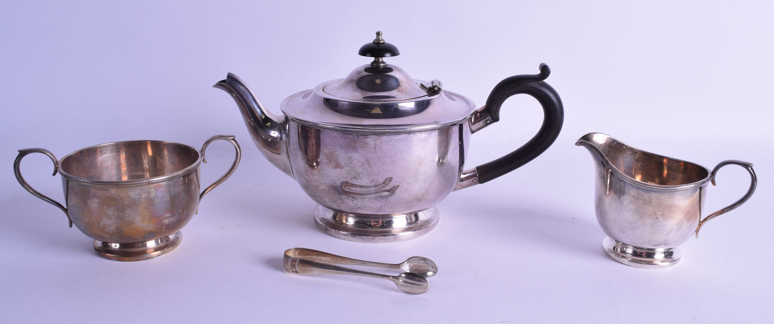 A SILVER PLATED THREE PIECE SILVER PLATED TEA SET by Harrods of London, together with a pair of