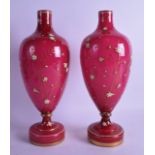A PAIR OF VICTORIAN ENAMELLED PINK GLASS VASES painted with extensive floral sprays. 32 cm high.