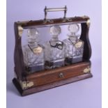A LATE VICTORIAN/EDWARDIAN SILVER PLATED OAK TANTALUS with three decanters and stoppers. 35.5 cm
