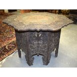 A LARGE INDIAN PETAL SHAPED WOODEN TABLE CARVED WITH FOLIAGE, inset with painted metal panel