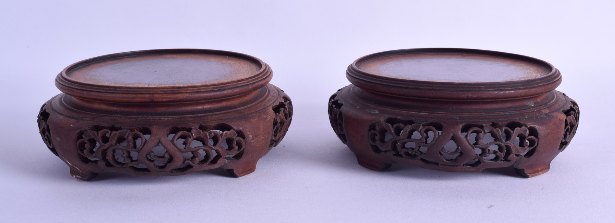 A PAIR OF EARLY 20TH CENTURY CHINESE CARVED HARDWOOD STANDS decorated with openwork foliage. 13.25