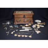 A MIXED QUANTITY OF JEWELLERY IN A WOODEN CASKET, including brooch's, watches, pendants etc. (qty)