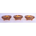 A SET OF THREE ART DECO SMOKEY AMBER AND RUBY GLASS BOWLS with angular supports and floral