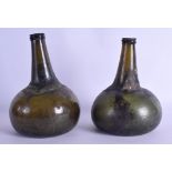 A NEAR PAIR OF 18TH CENTURY GREEN GLASS WINE BOTTLES of bulbous forms. 19 cm & 20 cm high.