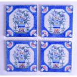 A SET OF FOUR 18TH CENTURY ENGLISH POTTERY TILES painted with urns of flowers upon a blue ground. 13