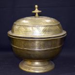 A LARGE EASTERN BRASS BOWL AND COVER, engraved with symbols and foliage. 31 cm high.