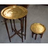 AN ENGRAVED EASTERN BRASS TRAY TOP TABLE, together with another smaller. (2)