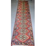 A GOOD ANTIQUE RED GROUND RUNNER, decorated with symbols and motifs. 280 cm x 70 cm.