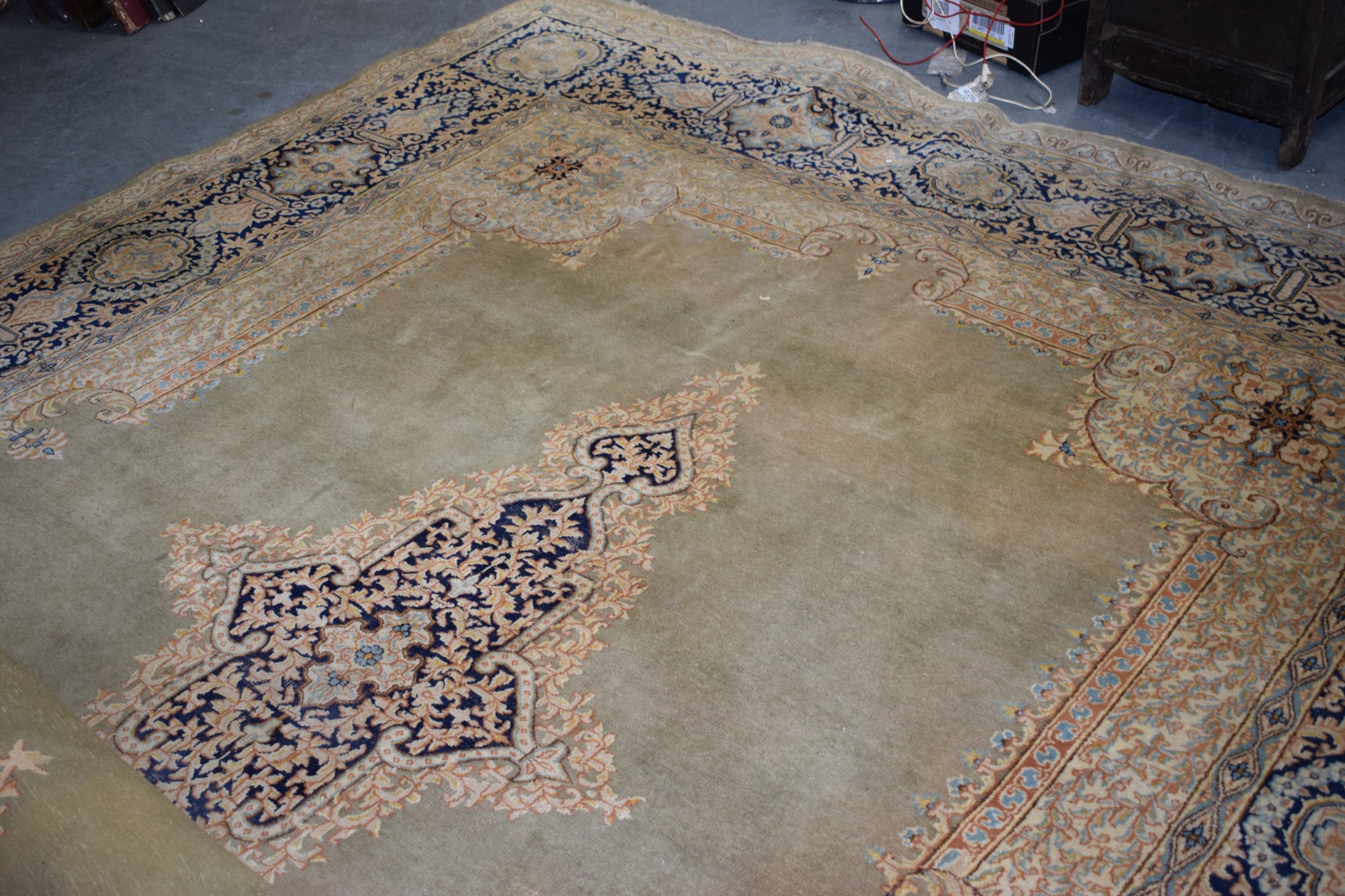 A VERY LARGE GREEN GROUND PART SILK CARPET decorated with motifs.