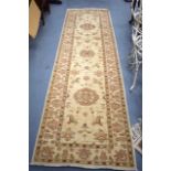 A MODERN BEIGE GROUND RUNNER, decorated with flowers. 287 cm x 30 cm.