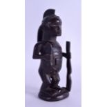 AN AFRICAN TRIBAL CARVED HARDWOOD FIGURE OF A MALE modelled holding a gun & knife. 18.5 cm high.