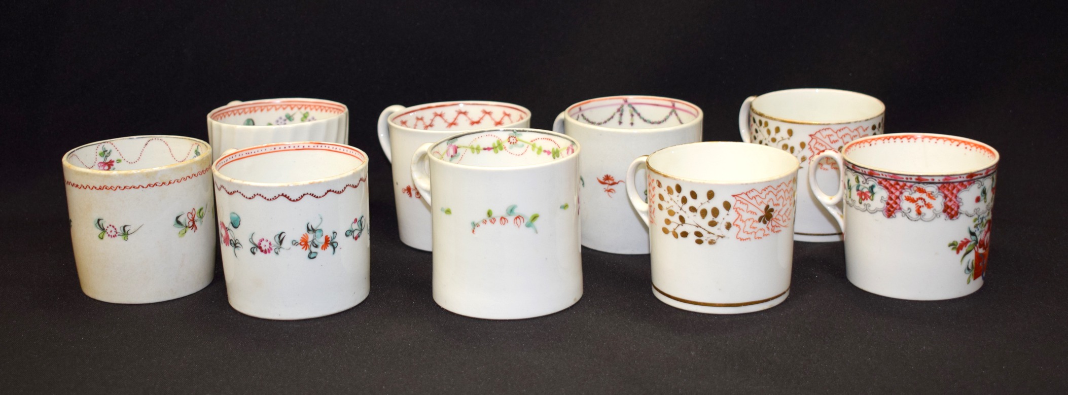 A GROUP OF NINE GOOD NEW HALL PORCELAIN COFFEE CUPS, of varying pattern.