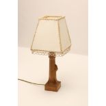 A ROBERT THOMPSON ADZED OAK TABLE LAMP BASE, of swept square section with leaf angles, and carved