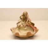 AN ART NOUVEAU ROYAL DUX BISQUE PORCELAIN FIGURAL CENTREPIECE, modelled as a young girl seated on