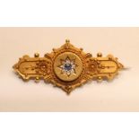 A LATE VICTORIAN 15CT GOLD BROOCH, the central roundel set with a sapphire and diamond star within a