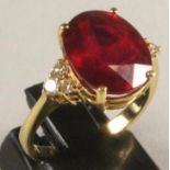 A RUBY RING, the oval facet cut stone of approximately 7cts, claw set to triangular shoulders each