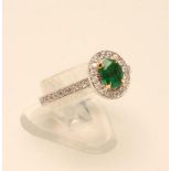 AN EMERALD AND DIAMOND CLUSTER RING, the oval facet cut Colombian emerald claw set to a border of