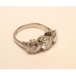 A THREE STONE DIAMOND RING, the central brilliant cut stone of approximately 1.55cts claw set and