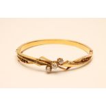A VICTORIAN GOLD STIFF HINGED BANGLE, the upper section centrally claw set with three old