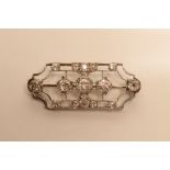 AN ART DECO DIAMOND BROOCH, the white metal open frame centred by three brilliant cut stones to a