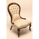 A VICTORIAN WALNUT FRAMED NURSING CHAIR of spoonback form button upholstered in a floral ivory