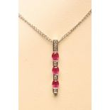 A RUBY AND DIAMOND LINE PENDANT, the 9ct white gold bar open back collet set with three diamonds and