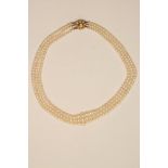 A TRIPLE STRAND CULTURED PEARL NECKLACE, the graduated pearls strung to a 9ct gold flower clasp