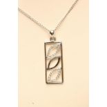 A 9CT WHITE GOLD DOUBLE PENDANT of oblong form, one centred by a plain leaf panel, the other with