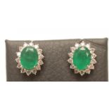 A PAIR OF EMERALD AND DIAMOND CLUSTER EAR STUDS, the oval facet cut emeralds claw set to a border of