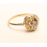 A VICTORIAN DIAMOND CLUSTER RING, the central brilliant cut cinnamon stone claw set to a border of