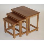 A ROBERT THOMPSON ADZED OAK NEST OF TABLES of oblong form, raised on faceted and block supports