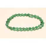 A SINGLE STRING OF AUSTRALIAN JADE BEADS, the fifty six faceted beads with double emerald facet