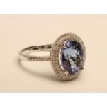 A TANZANITE AND DIAMOND CLUSTER RING, the oval cut tanzanite of approximately 3.85cts, claw set to a