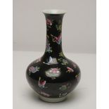 A CHINESE PORCELAIN BOTTLE VASE, painted in famille rose enamels with scattered flowerheads and