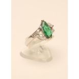 AN EMERALD AND DIAMOND RING, the oval facet cut Colombian emerald claw set to open shoulders each