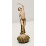 AN ART DECO ROYAL DUX BISQUE PORCELAIN FIGURE, modelled as a semi-nude maiden, her left arm raised