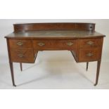 AN EDWARDIAN MAHOGANY DESK of bowed form with stringing and chequer banding, the green leather lined