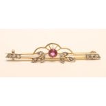 A LATE VICTORIAN 15CT GOLD BROOCH, centred by an open back collet set red tourmaline with rose cut