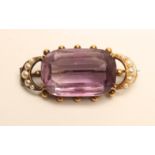 A LATE VICTORIAN AMETHYST BROOCH, the rectangular facet cut stone claw set between two seed pearl