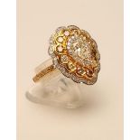 A DIAMOND CLUSTER RING, the central pear cut yellow stone claw set to a border of eighteen small
