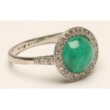 AN EMERALD AND DIAMOND RING, the circular cabochon polished emerald collet set to a border of