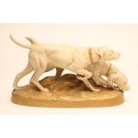 A ROYAL DUX BISQUE PORCELAIN MODEL OF A POINTER AND RETRIEVER, early 20th century, on a