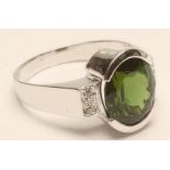 A TOURMALINE AND DIAMOND RING, the oval facet cut tourmaline open back collet set to oblong