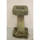 A SANDSTONE BIRD BATH of rough hewn square form with square tapering column and mildly domed base,