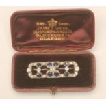 AN ART DECO SAPPHIRE AND DIAMOND BROOCH, of open canted oblong form open back collet set with