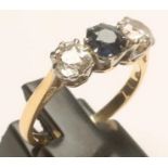 A SAPPHIRE AND DIAMOND THREE STONE RING, the central facet cut sapphire claw set and flanked by