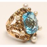 A COCKTAIL RING, the all-over facet cut oval blue topaz claw set to an open wire panel with six